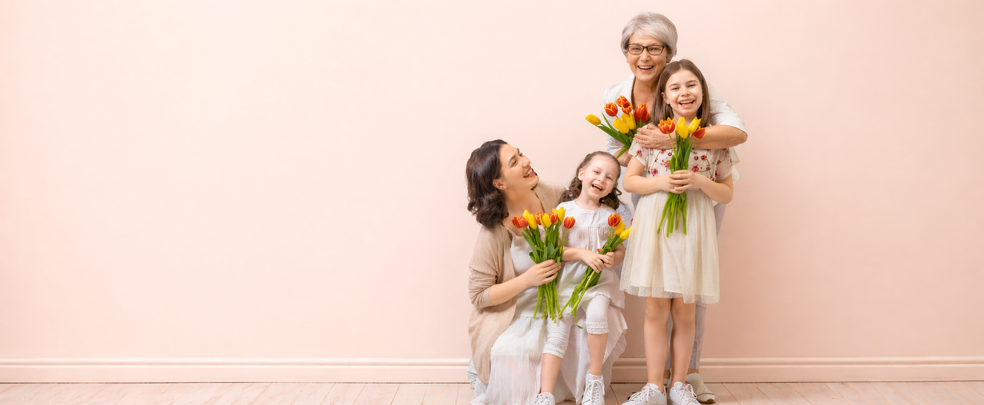 Family with three generations holding tulip bouquets against a light pink wall